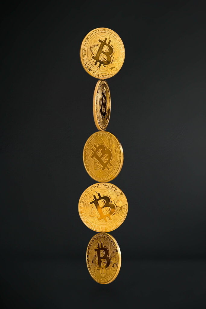 Vertical stack of shiny gold Bitcoin coins on dark background digital currency wallpaper