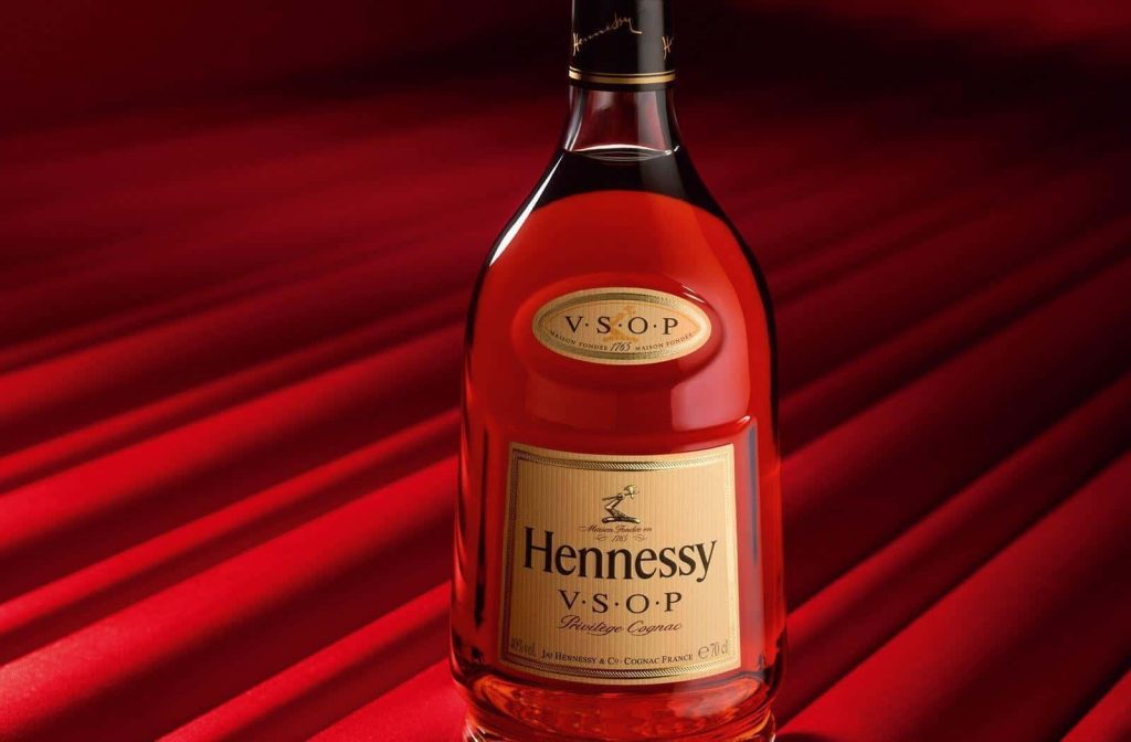 Hennessy VSOP Privilège Cognac bottle on pleated red background with warm amber lighting wallpaper