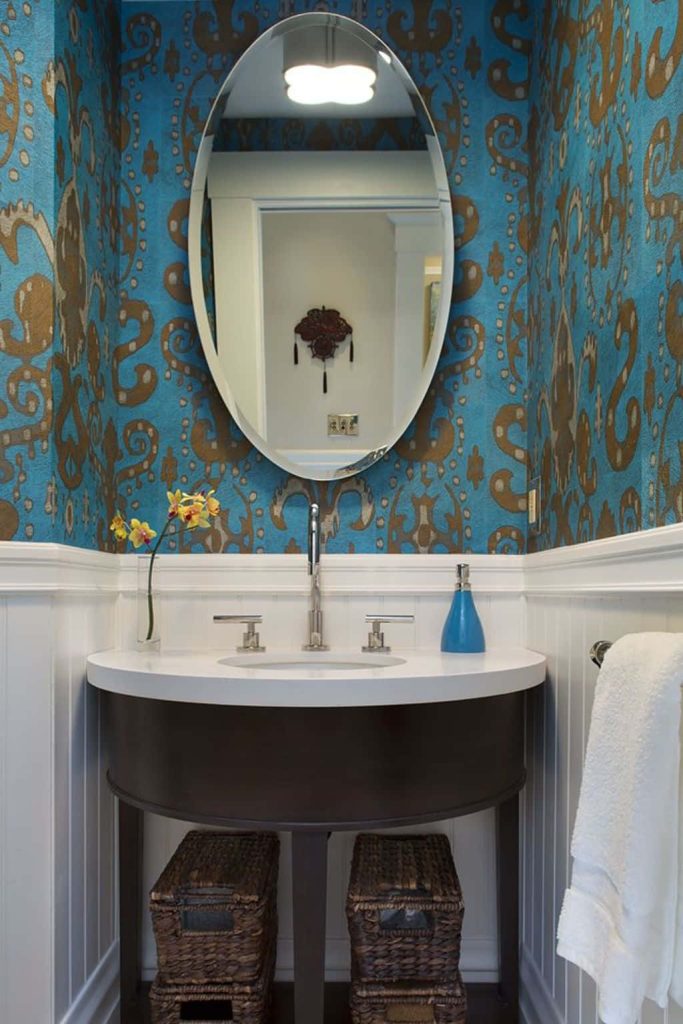 Modern bathroom with turquoise bronze damask wallpaper dark wood vanity oval mirror white wainscoting