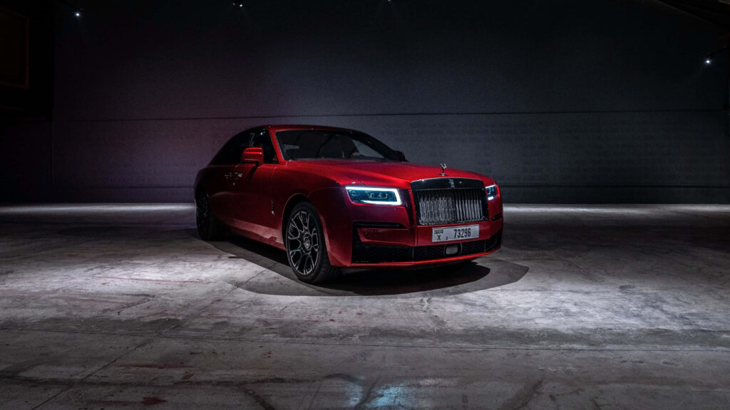 Red Rolls Royce Phantom in dimly lit room with polished body and iconic grille luxury wallpaper