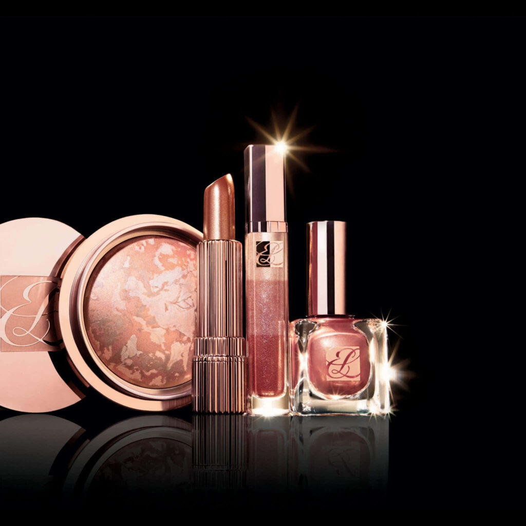 Rose gold makeup essentials with lipstick lip gloss pressed powder nail polish on black background Wallpaper