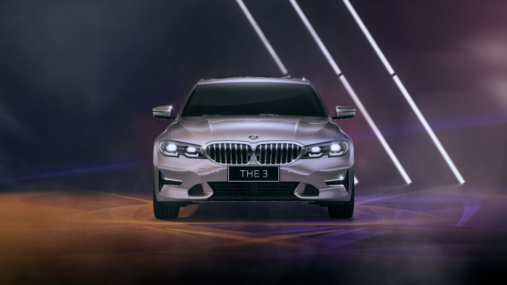 Luxurious silver BMW with bright white lights against a modern colorful wallpaper background