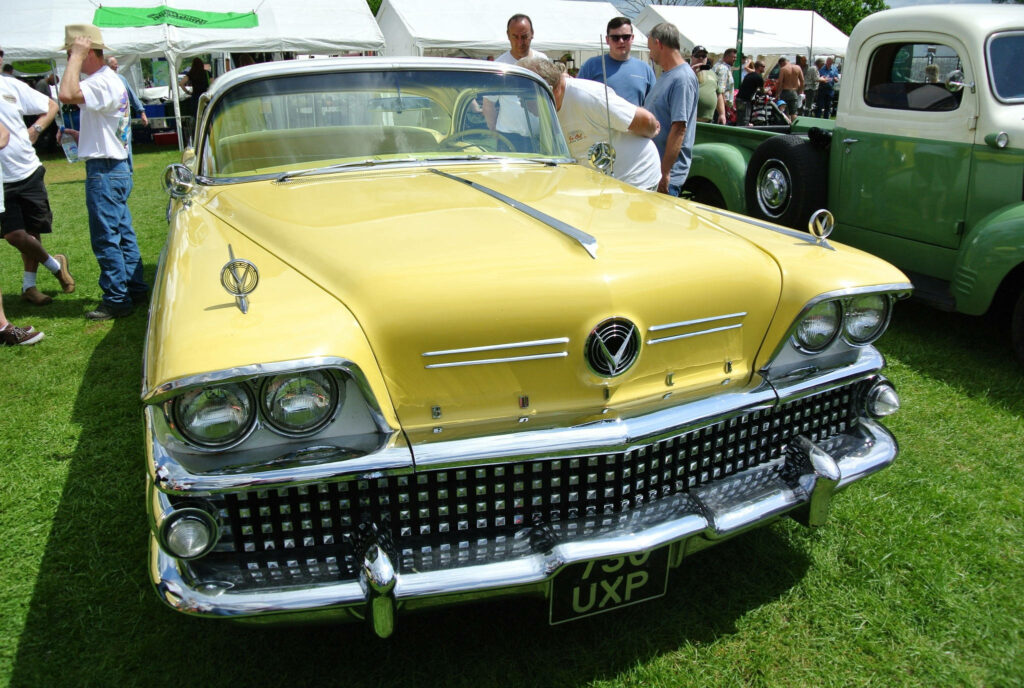 Luxurious yellow Buick Limited at outdoor car show with classic cars and enthusiasts around Wallpaper