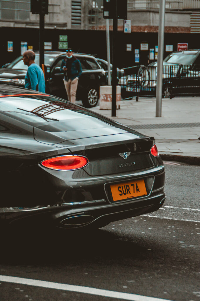 Luxury Bentley with unique license plate parked on modern city street urban style wallpaper