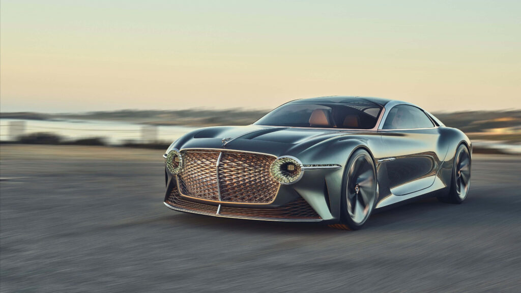 Luxurious blue Bentley with bold grille driving on open road at serene sunset wallpaper background