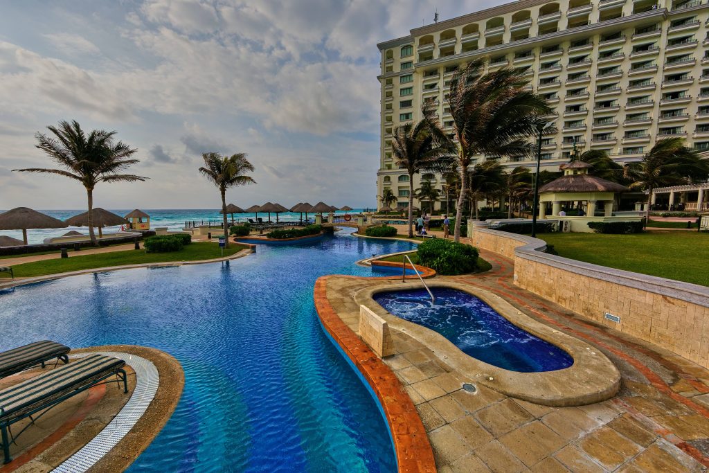 Luxury Cancun hotel pool with jacuzzi palm trees ocean view tropical relaxing wallpaper background