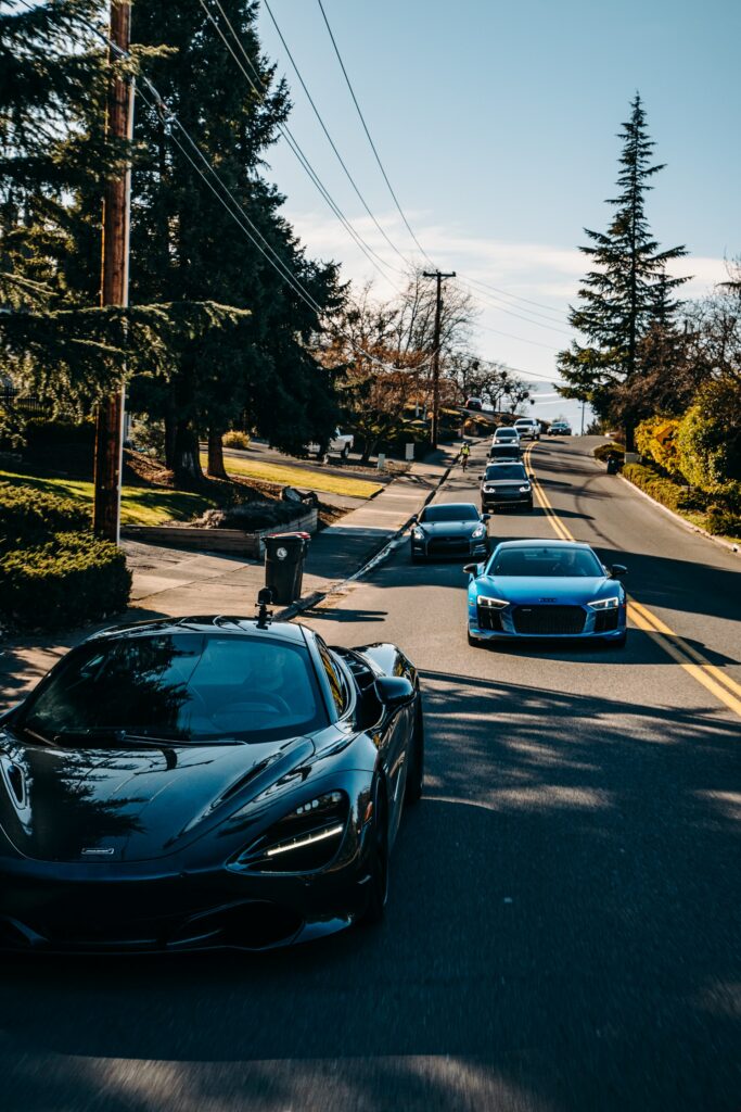 Luxury Cars in Motion: Scenic Drive Under Clear Blue Sky Wallpaper