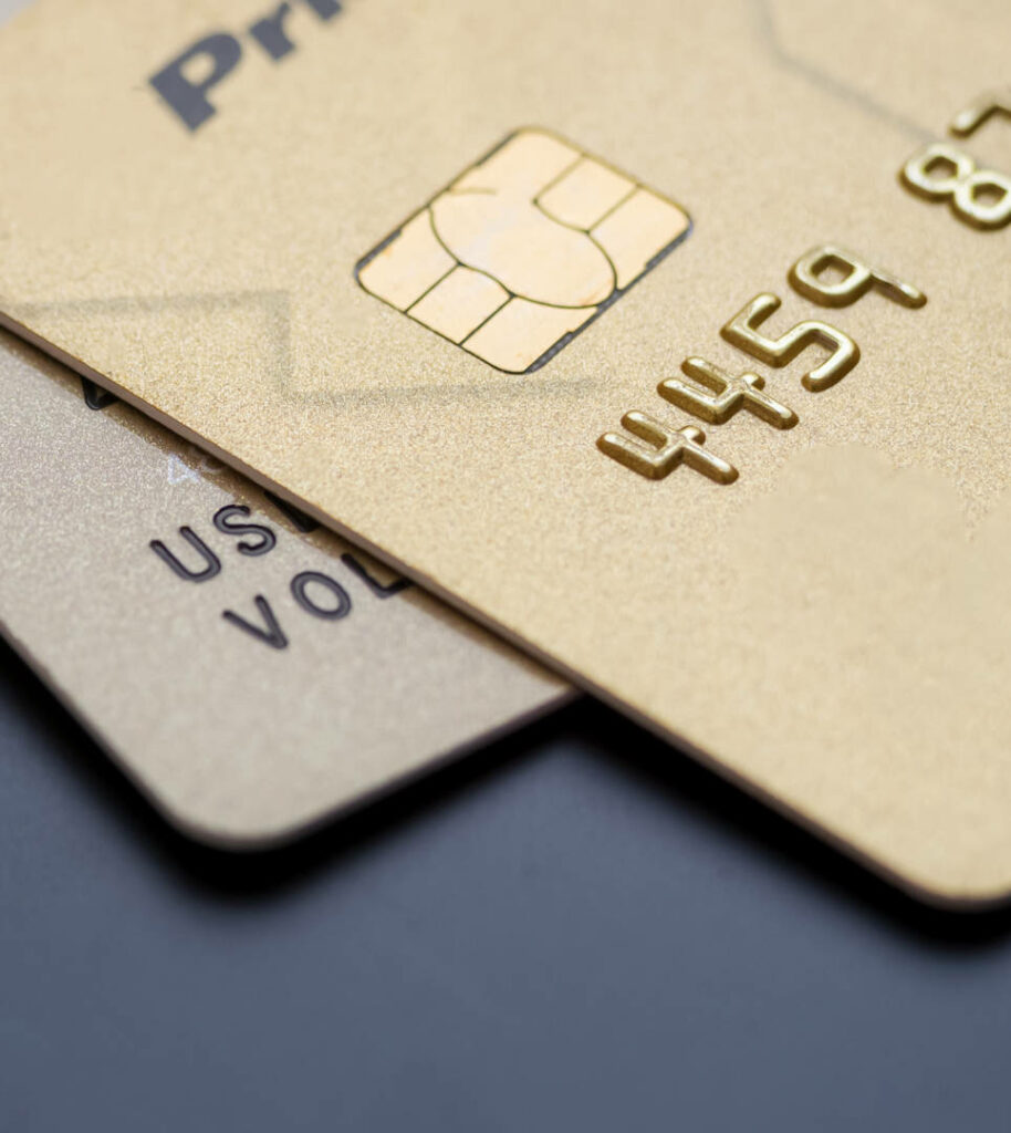 Close up of two gold credit cards stacked showing embossed details and chip on dark background Wallpaper