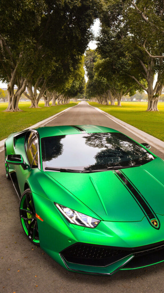 Green luxury sports car parked on tree-lined road with glossy finish reflecting nature background Wallpaper
