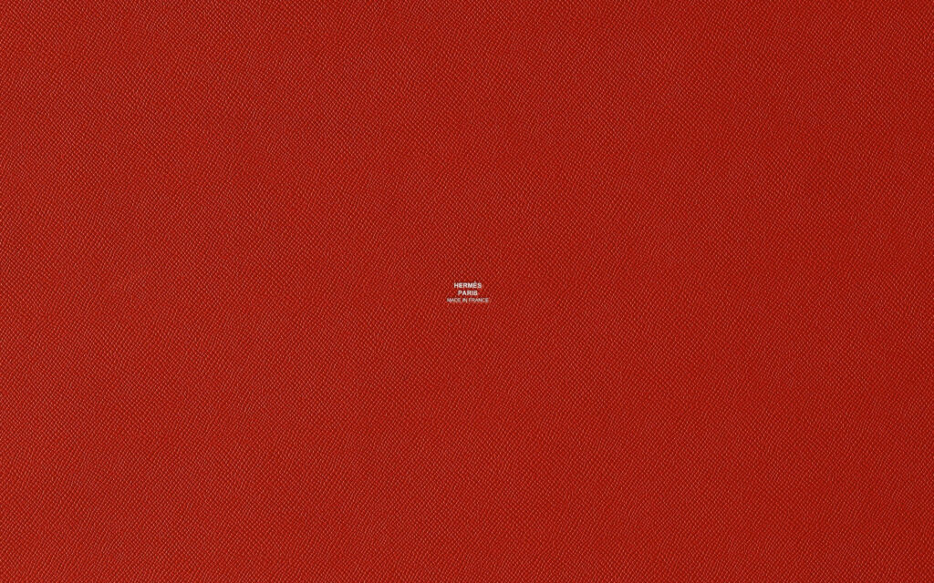 Hermès logo embossed on textured red luxury wallpaper background inspired by signature bag