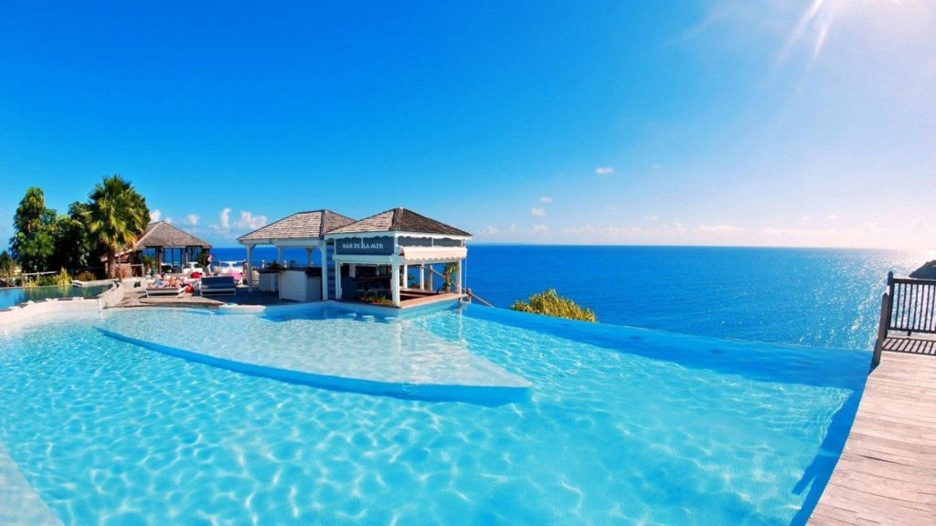 Luxury infinity pool ocean view with Bar de la Mer poolside bar and tropical wooden deck beach house Wallpaper