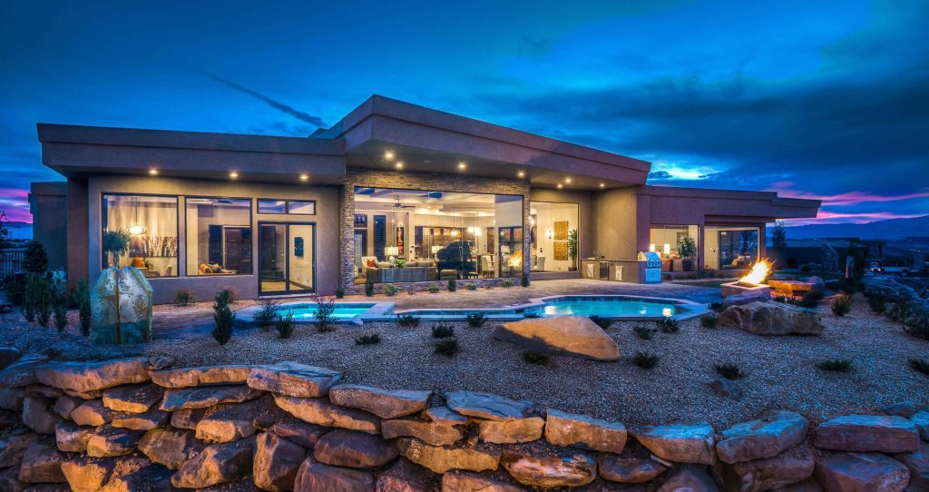 Luxury modern house at night with glowing interiors pool fire pit twilight desert landscape wallpaper
