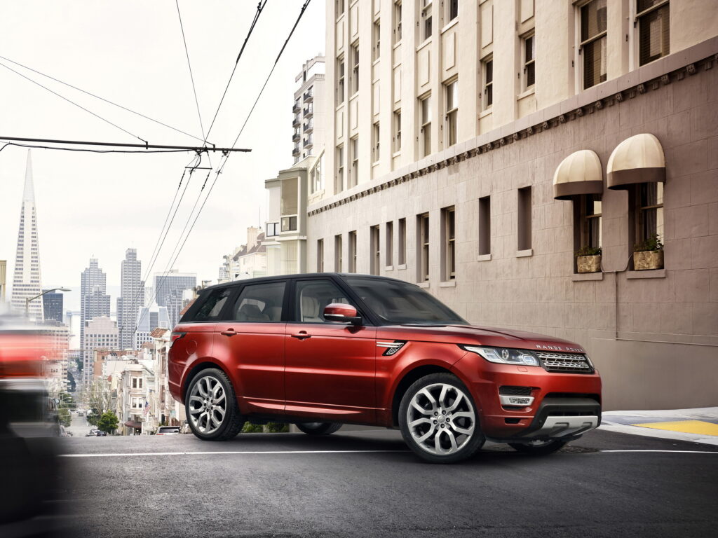 Luxury Red Land Rover Range Rover SUV in Urban Cityscape Wallpaper