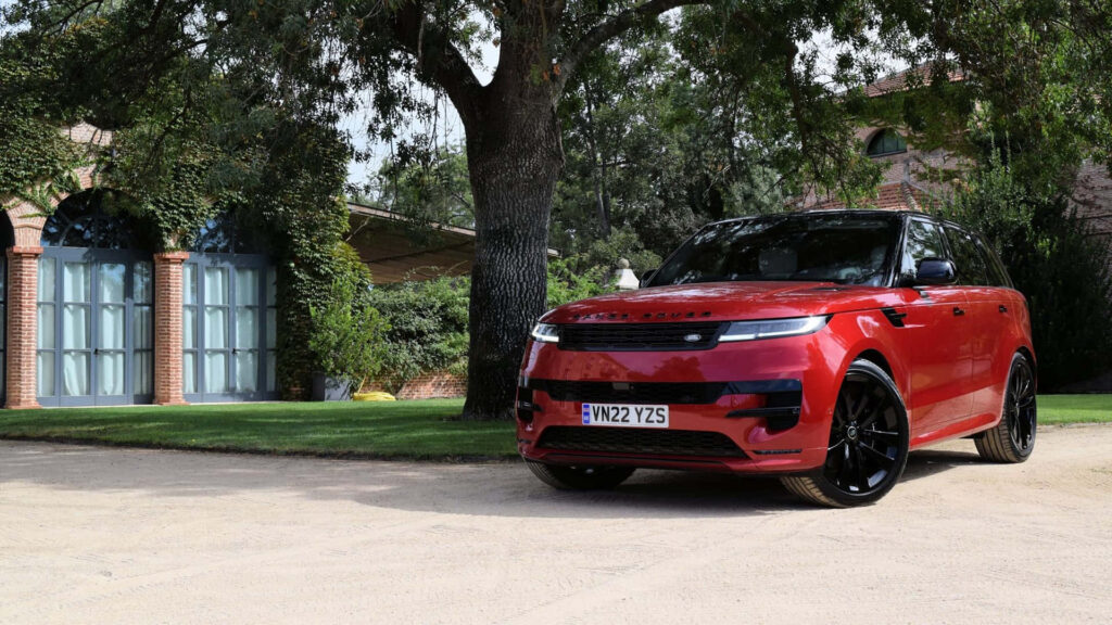 Luxury Red Range Rover Parked by Elegant Greenery Wallpaper
