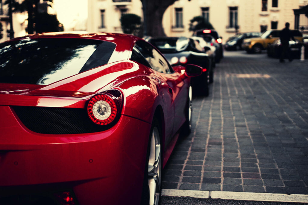 Rear view of luxury sports car with glossy red tail light on city street wallpaper background