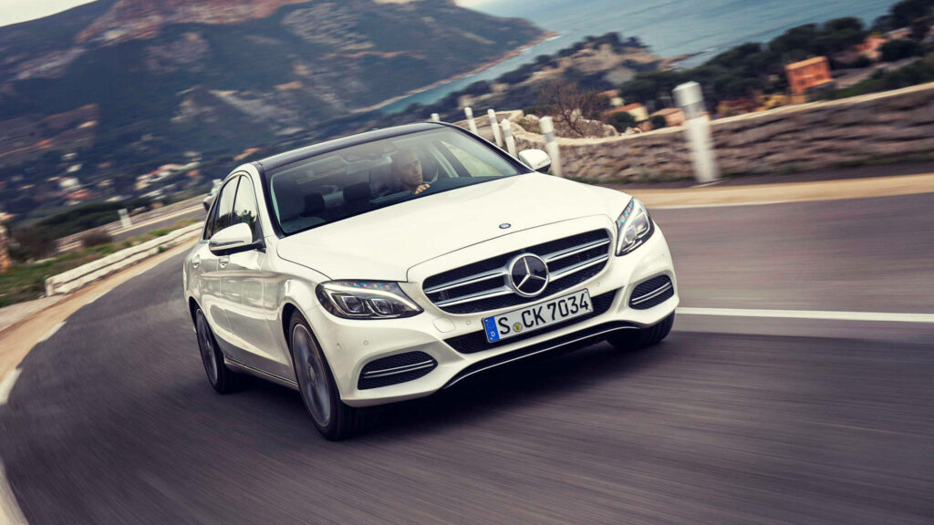 Luxury white Mercedes-Benz driving on scenic coastal road elegant dynamic performance wallpaper
