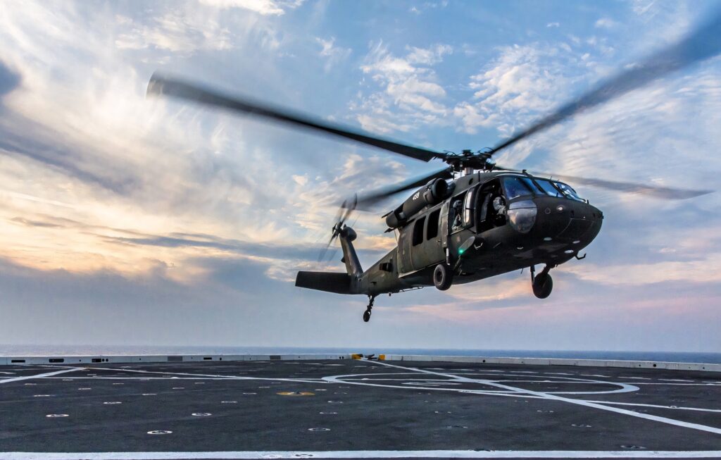 MH-60M Black Hawk helicopter flying over naval ship deck with dramatic sky background Wallpaper