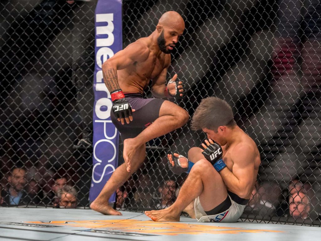 Demetrious Johnson towering over Henry Cejudo inside the Octagon in intense UFC battle wallpaper
