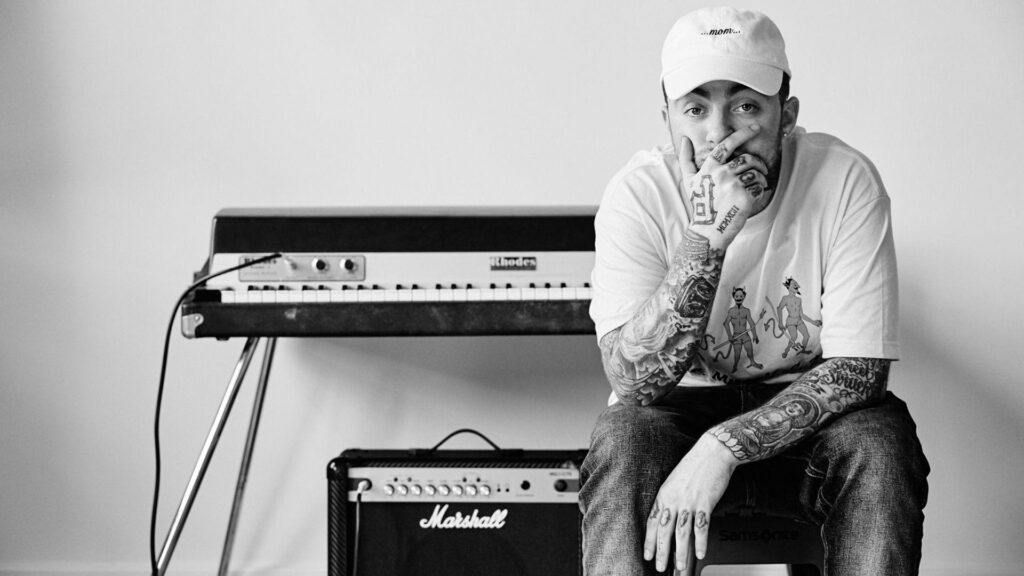 Mac Miller's Relaxed Style: A Celeb Sitting on a Piano-Themed Chair, Sporting a White T-Shirt and Cap - HD Wallpaper