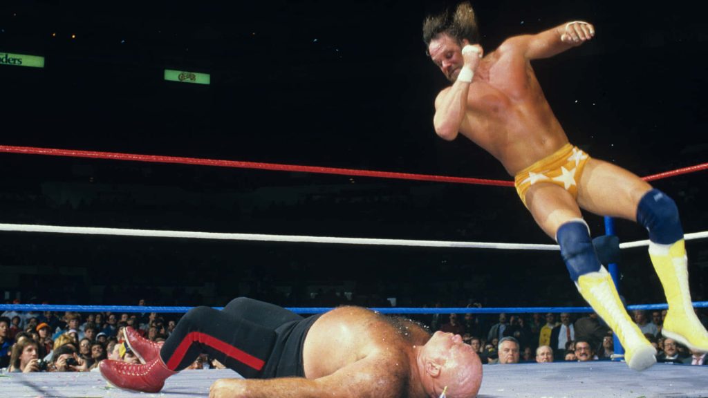 Macho Man Randy Savage leaps for high flying attack on George The Animal Steele in WWE ring Wallpaper
