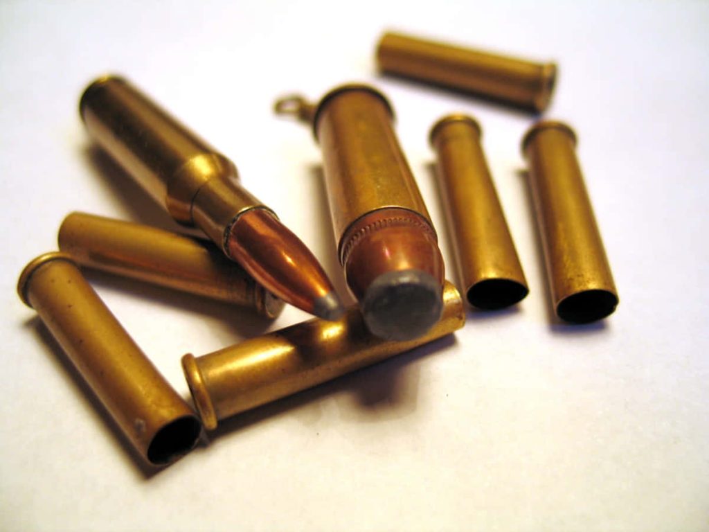 Macro shot of brass rifle cartridges and spent casings on white surface with metallic texture Wallpaper