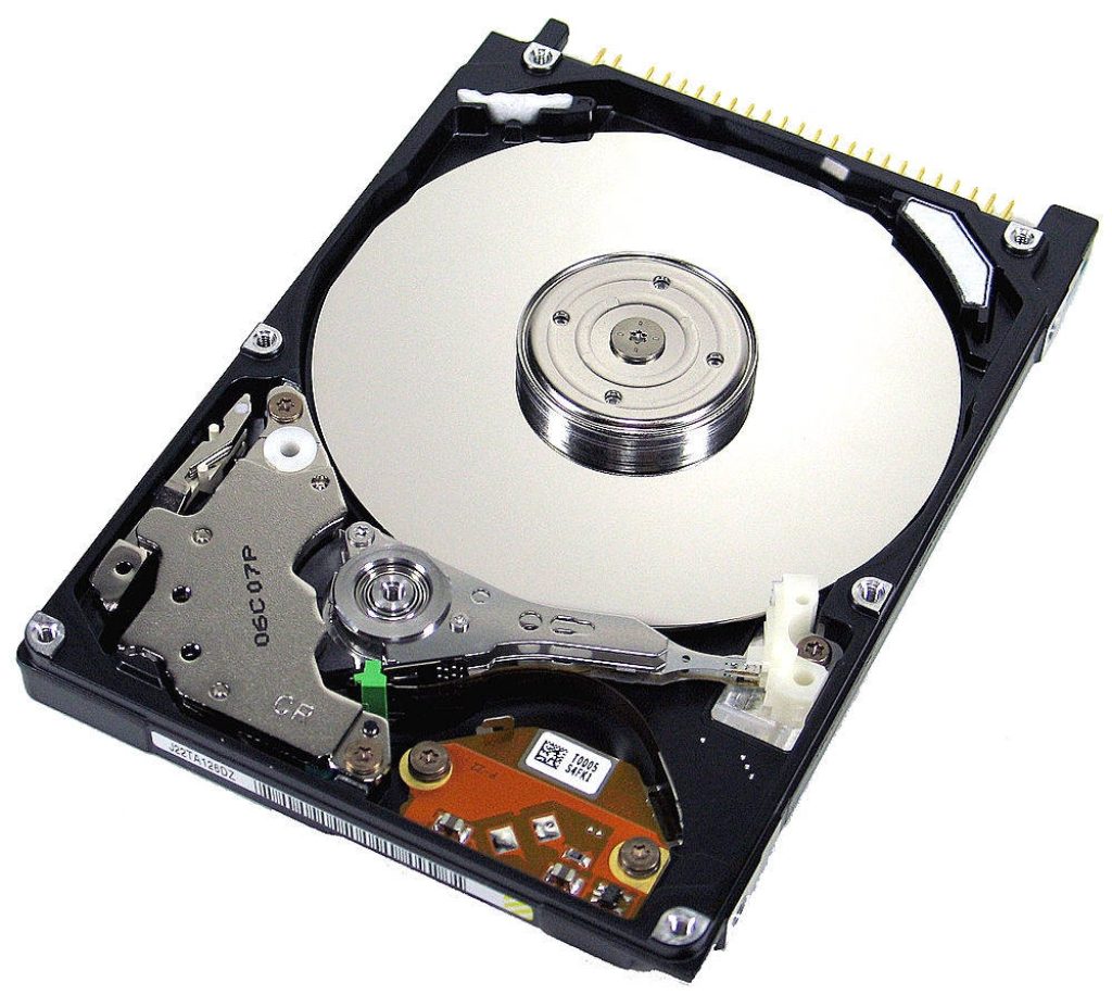 Top-down macro photo of an exposed computer hard disk drive with metallic platter and actuator arm Wallpaper