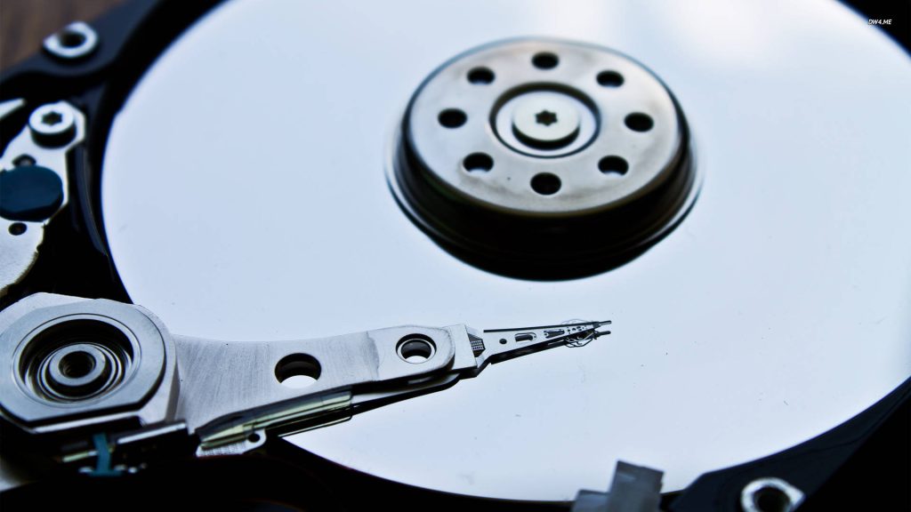 Macro close-up of reflective computer hard drive platter and precise readwrite actuator arm detail Wallpaper