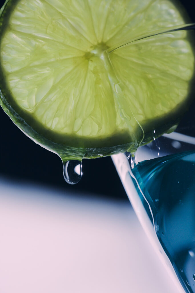 Vibrant Lime Slice Macro Over Blue Liquid: Refreshing Wallpaper