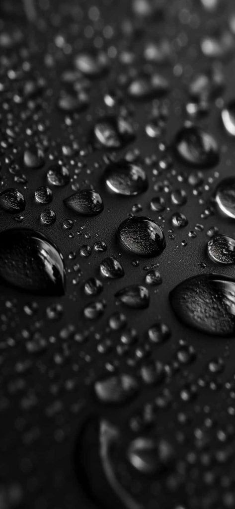 Macro wallpaper of clear water droplets on matte black surface with sharp reflective highlights