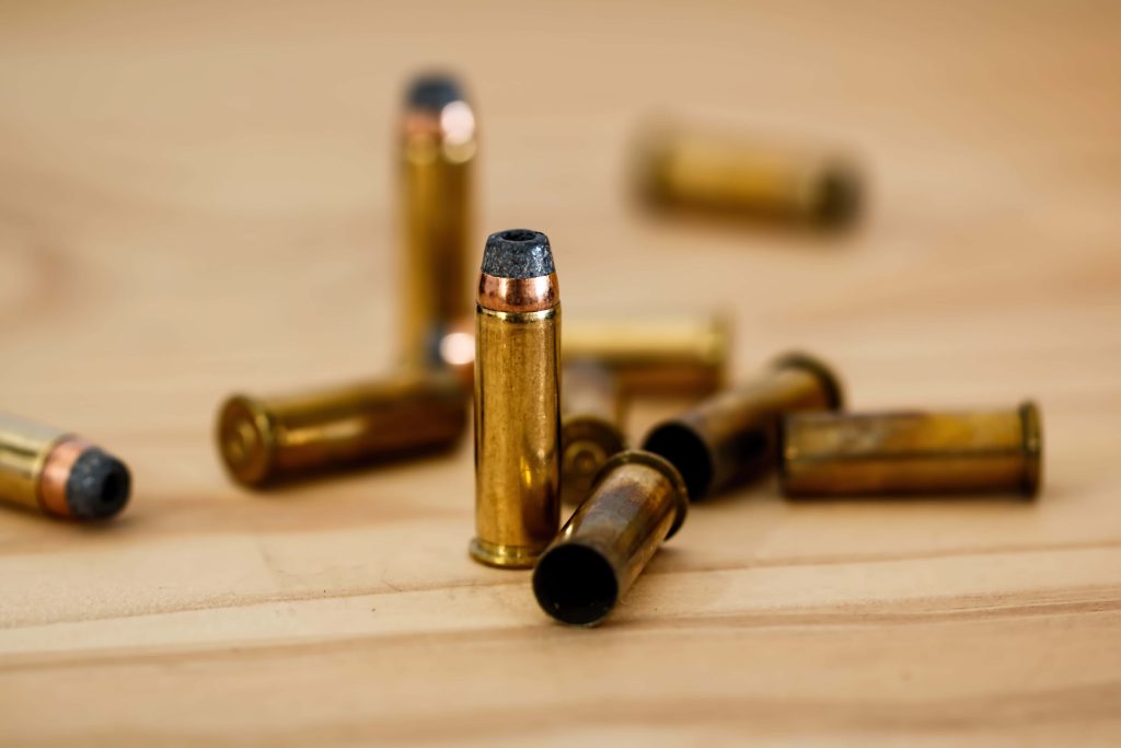 Close up of metallic handgun bullets on wood surface with single sharp focused cartridge tactical wallpaper