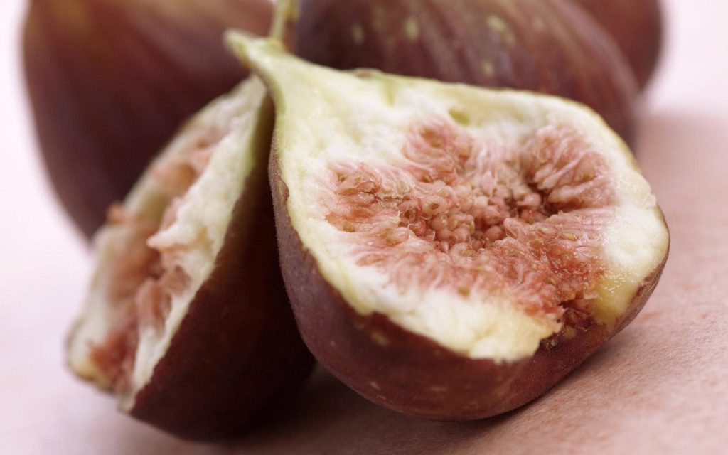 Macro photo of fresh halved figs showing pink flesh and purple skin with soft lighting Wallpaper