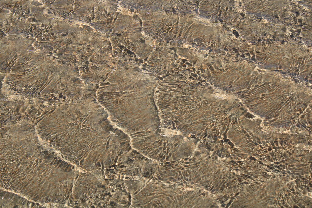 Intricate Macro View of Gentle Sea Waves on Sandy Terrain Wallpaper
