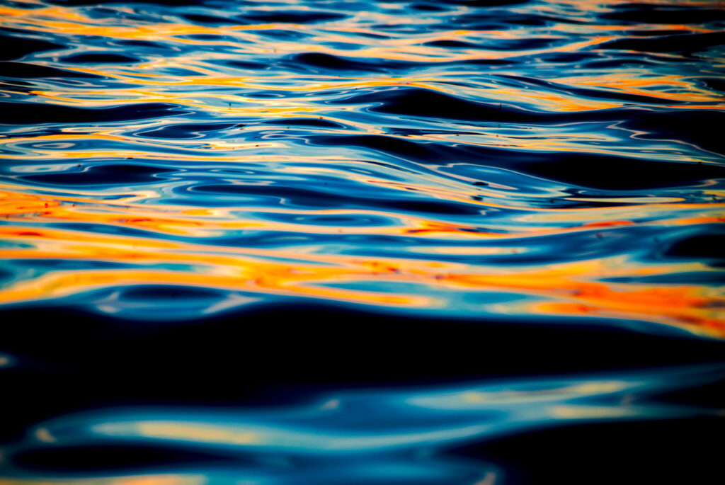 Macro view of sea waves with deep blue water and golden shimmering reflections wallpaper background