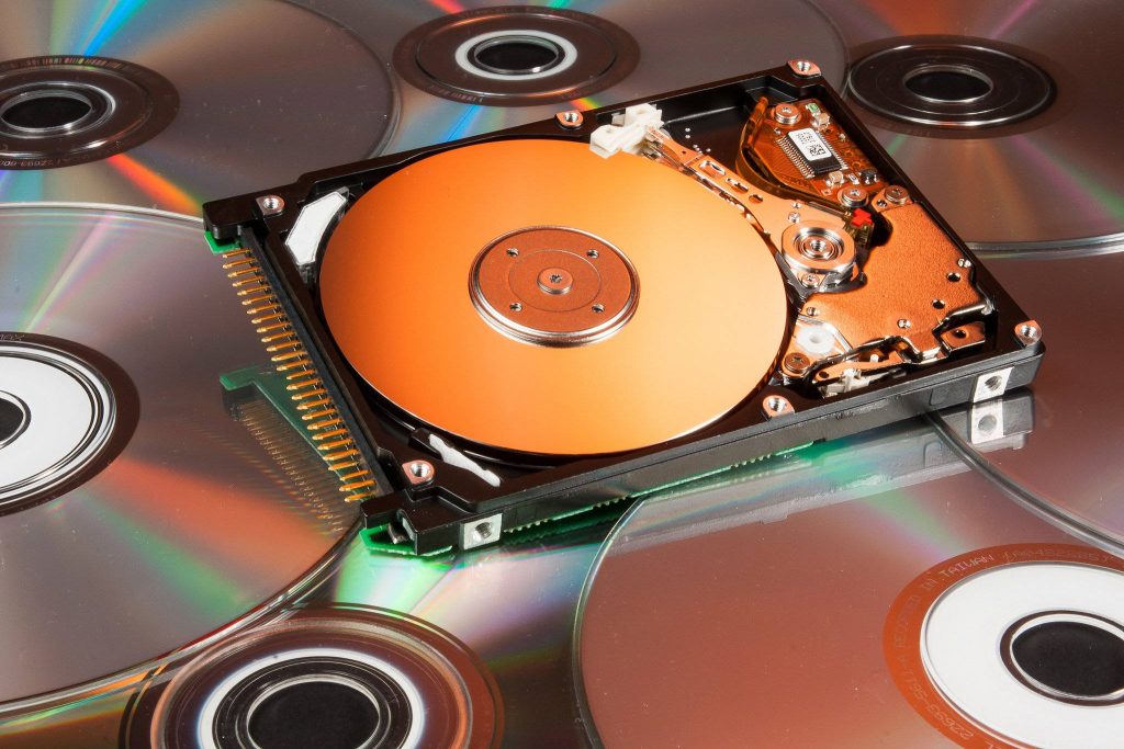 Macro shot of open hard disk drive with polished copper platter on shimmering compact discs background Wallpaper