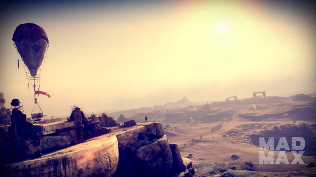 Desolate wasteland under hazy sky with hot air balloon rising above rugged Mad Max outpost Wallpaper