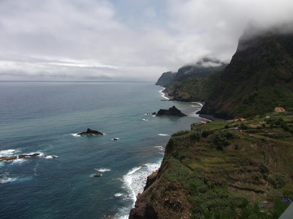 Madeira island rugged coastline with steep mountains misty peaks and green terraces by Atlantic Ocean Wallpaper