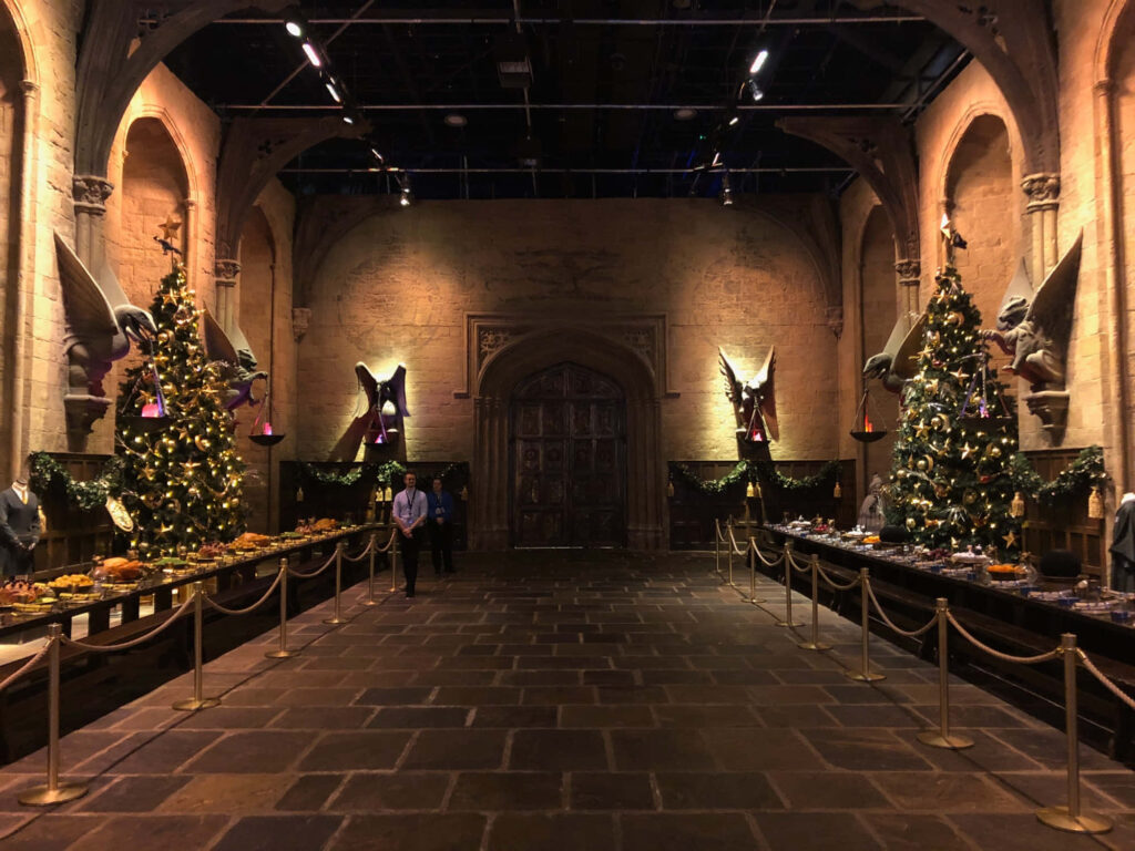 Enchanting Festive Hall with Towering Christmas Trees & Sparkling Decor Wallpaper