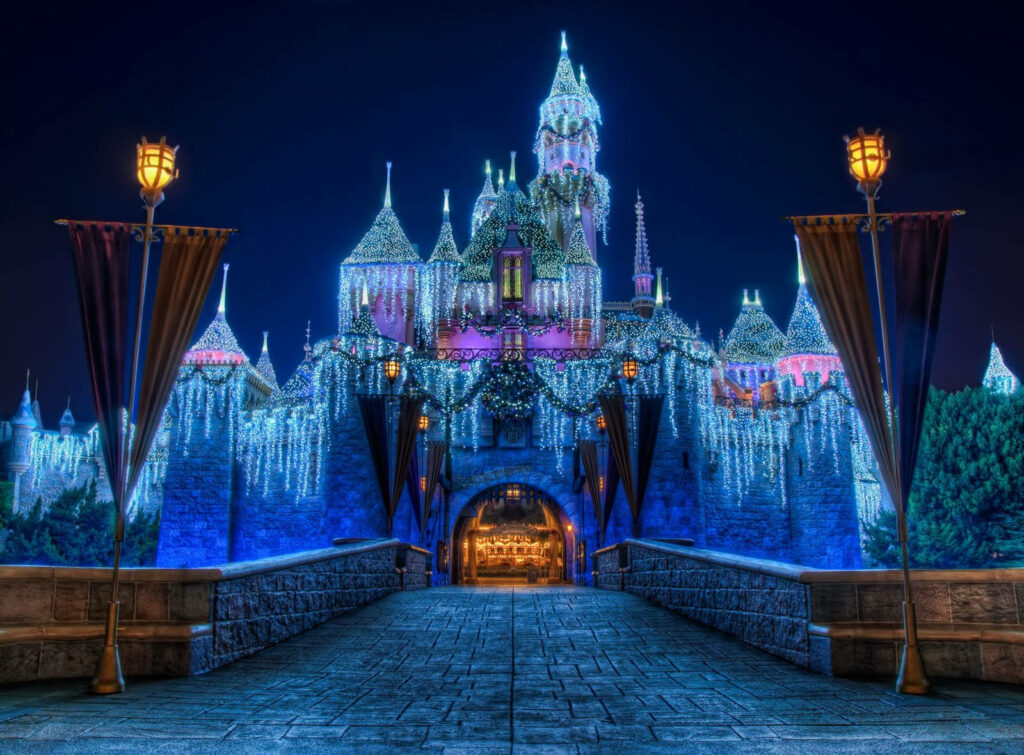 Disney Castle entrance illuminated with sparkling lights and festive decorations at night Wallpaper