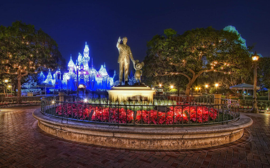 Enchanting Disney Park Night Scene: Festive Lights & Glowing Castle Wallpaper