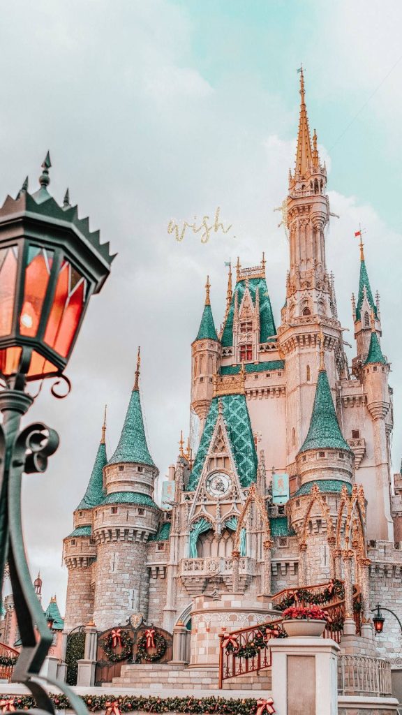 Disney World Cinderella Castle holiday wallpaper with festive wreaths golden wish text bright sky