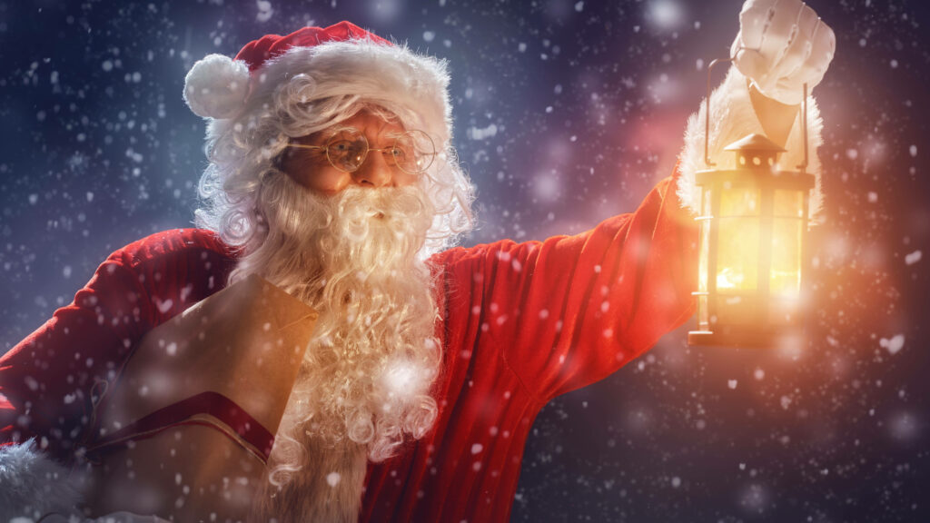 Santa Claus with Lantern in Magical Snowy Christmas Scene Wallpaper