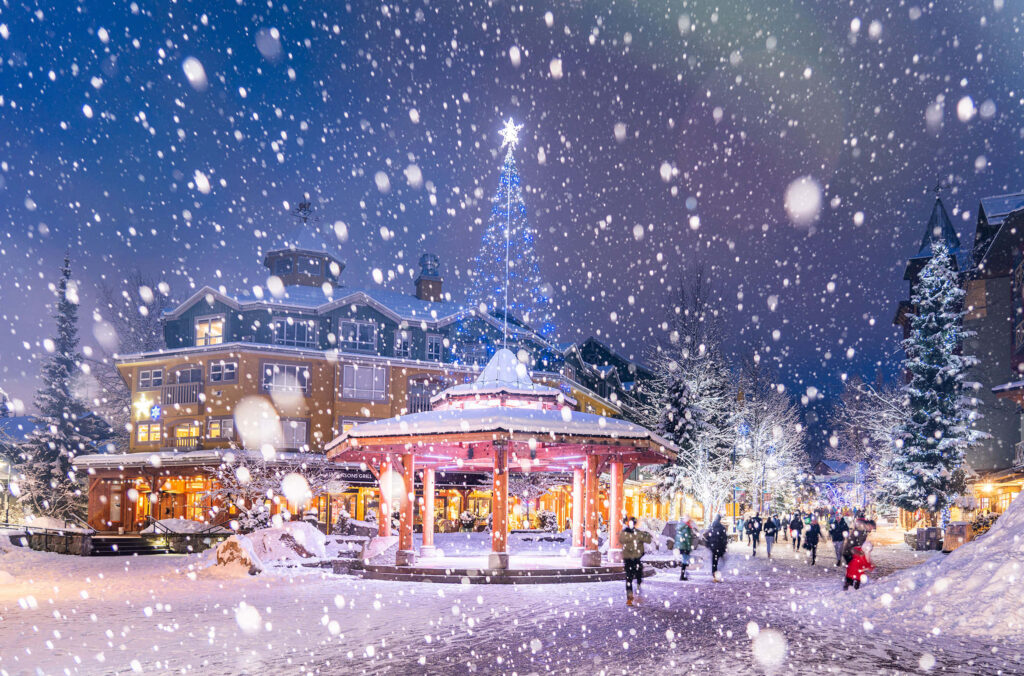 Enchanting Winter Wonderland: Illuminated Town Square Under Snow Wallpaper