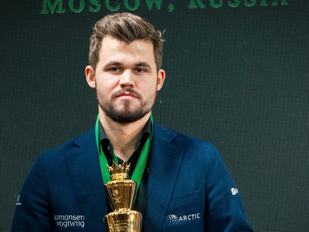 Magnus Carlsen Wallpaper: Champion with Golden Trophy - Chess Background