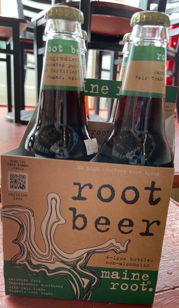 Close-up of Maine Root non-alcoholic root beer 4-pack in rustic cardboard carrier with green accents Wallpaper