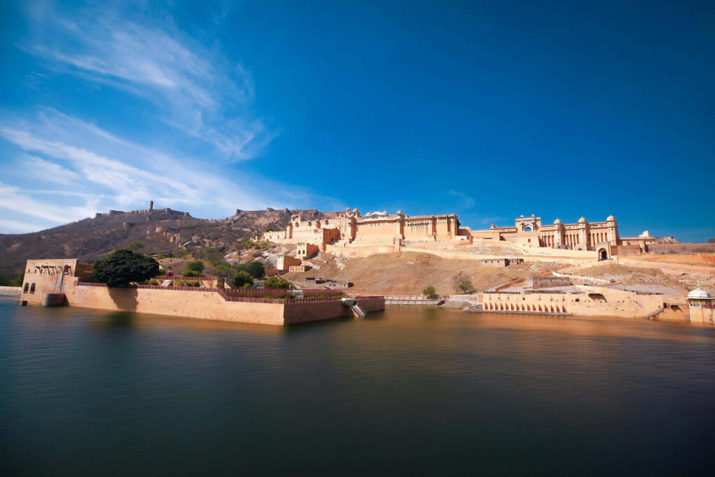 Amer Fort reflected in calm water under clear blue sky stunning wallpaper background view