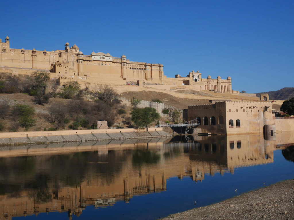Amer Fort majestic architecture reflected in tranquil lake under clear blue sky wallpaper background