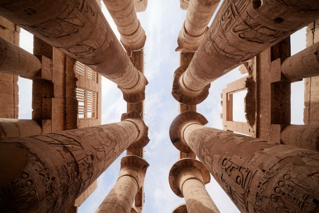 Ancient Egyptian columns with hieroglyphics viewed from below in warm sandy tones wallpaper