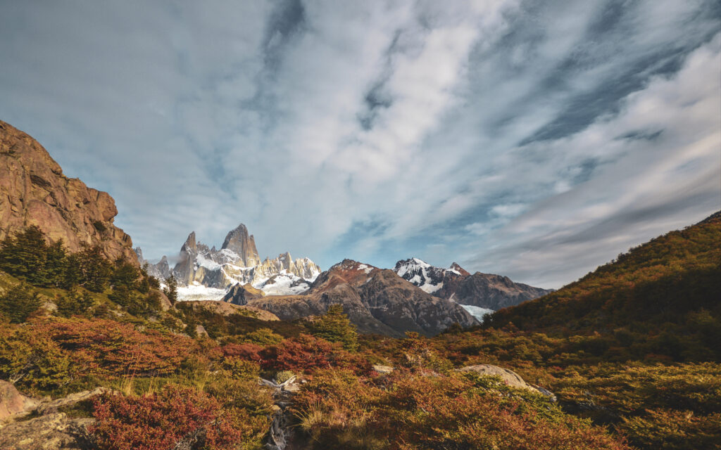 Breathtaking autumn mountain landscape with rugged rocks lush bushes and dramatic cloudy sky Wallpaper