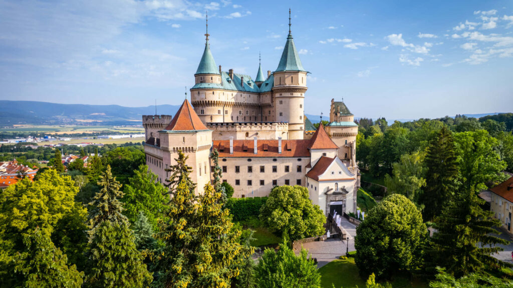 Majestic Bojnice Castle medieval fairytale in lush green landscape with rolling hills Slovakia view Wallpaper