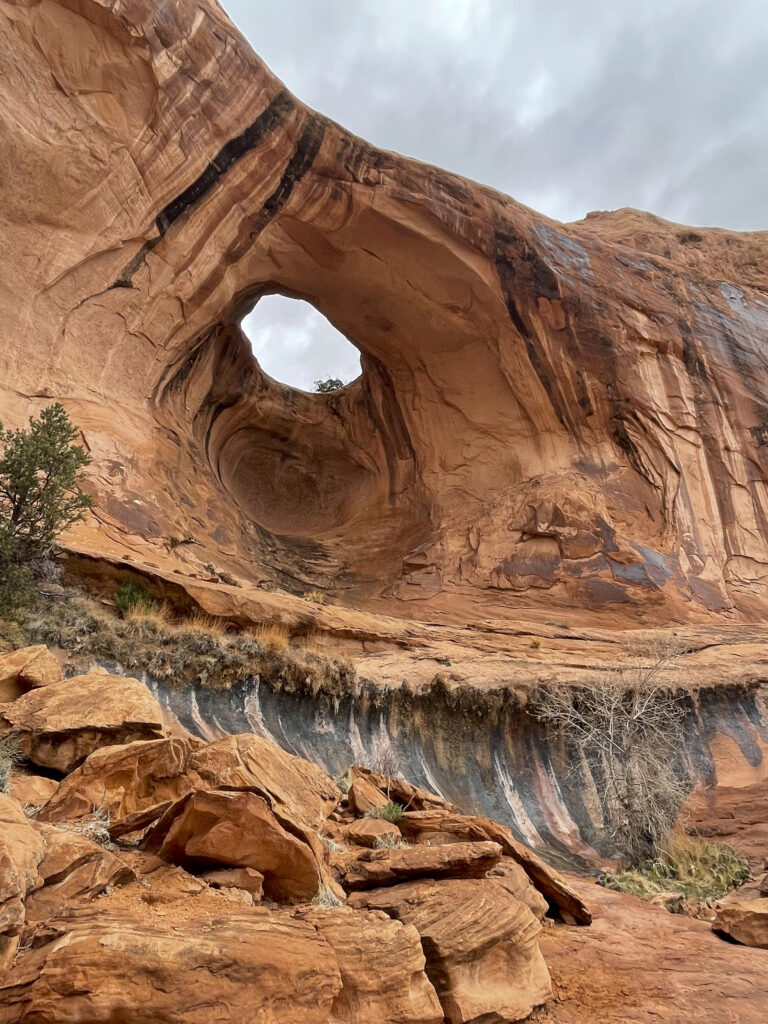 Majestic canyon with rugged brown rock formations and natural arch under soft cloudy sky wallpaper